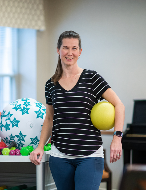 Woman with workout equipment holding weighted ball and smiling