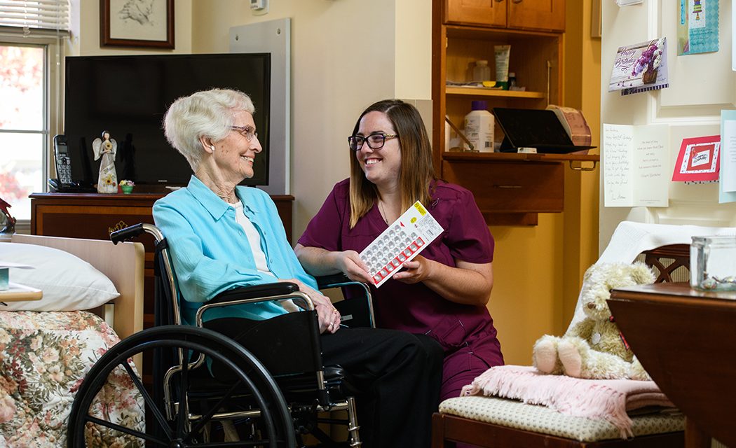 Woman in wheelchair with a nurse smiling and looking at a pamphlet