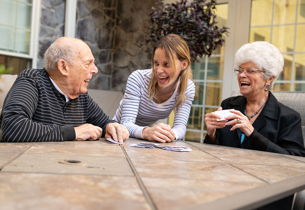 elderly couple playing cards and laughing with women