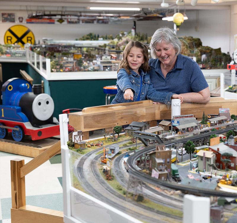 Woman and granddaughter exploring the train room at garden Sspot Village