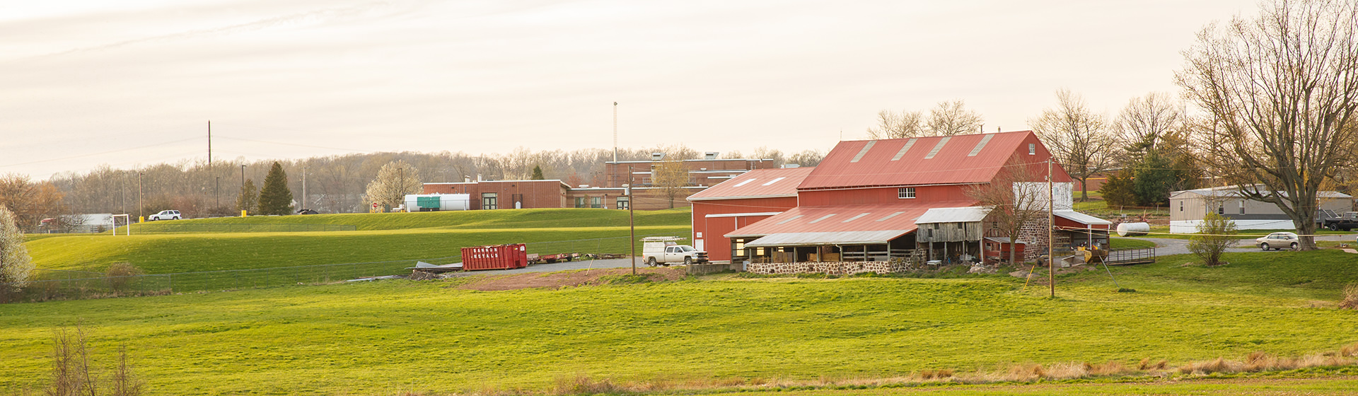 A red barn in a field with the sun setting