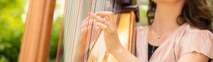 Woman with wedding band on plying the harp with multicolored chords